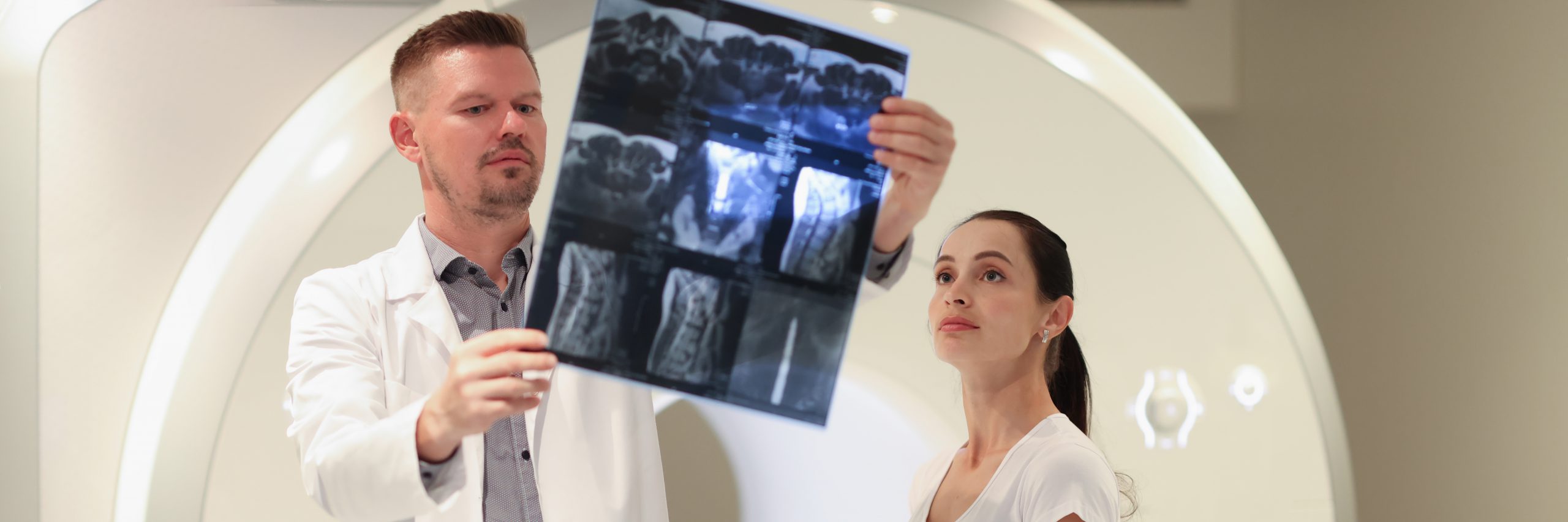 Doctor radiologist looking at snapshot of patient spine in front of mri machine